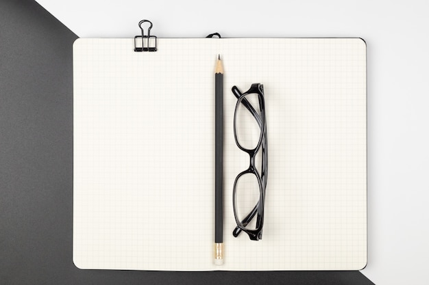 Top view of an emptry grid notebook with pencil and eyeglasses