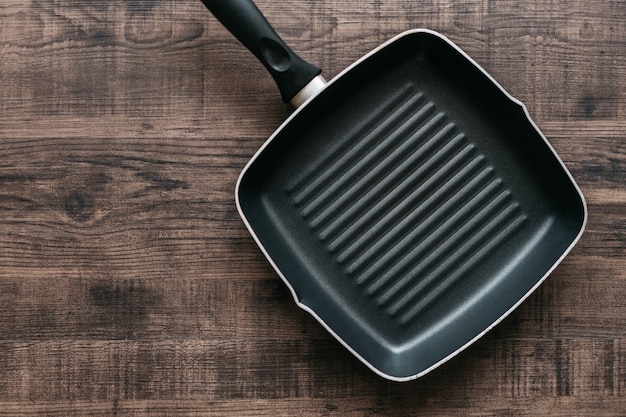 Top view of the empty non-stick square frying pan over wooden kitchen counter background with copy space.