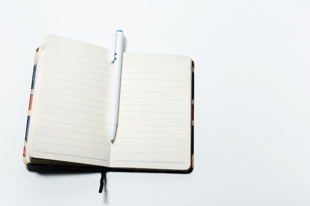 Top view of empty notebook and pen, on white background.