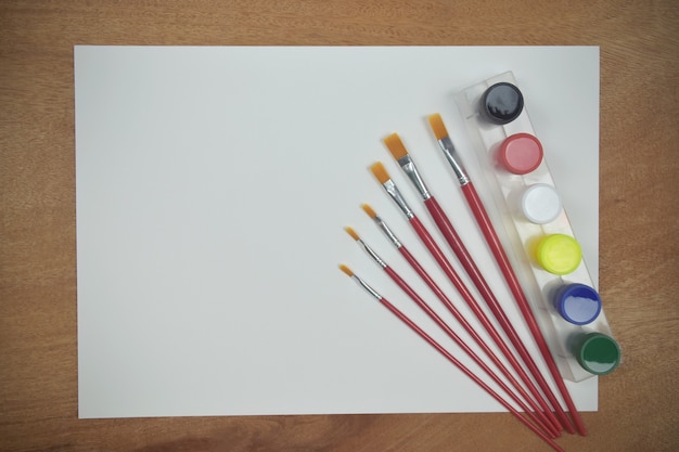 Top view of empty paper with art palette watercolor and a brush on wooden background