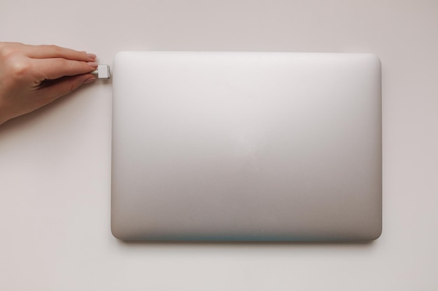 Top view of female hand holding the power plug of pc notebook laptop power