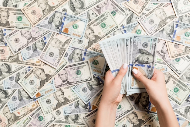 Top view of female hands counting money on dollar background. 