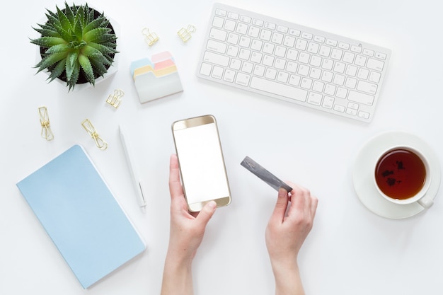 Top view of female hands holding credit card wile making online payment on laptop computer, flat lay