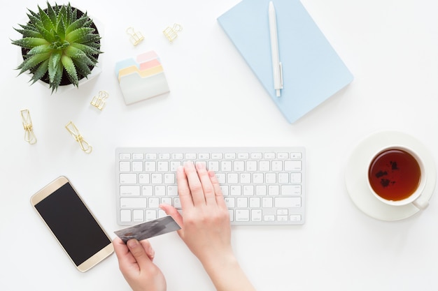 Top view of female hands holding credit card wile making online payment on laptop computer, flat lay