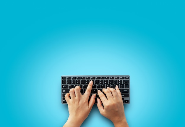 Top view of female hands on modern computer keyboard. Isolated over on blue background, Simple design, blank copy space for your designs