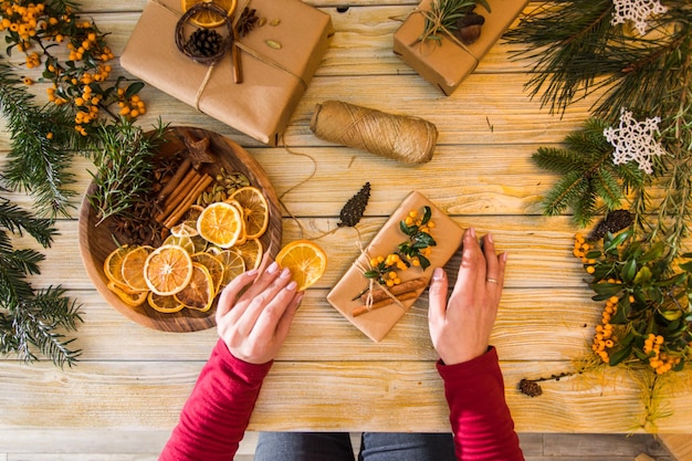 Top view of female hands at the table Process of packing Christmas gifts