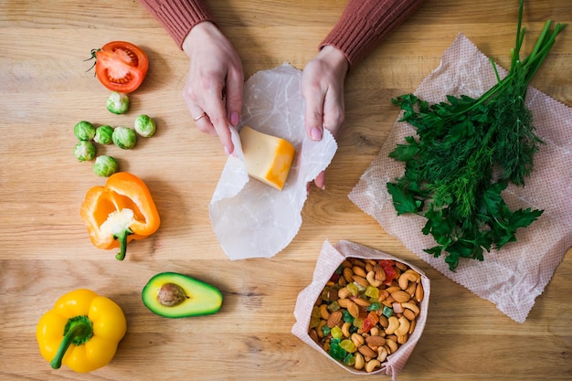 Top view of female hands wrapping cheese into beeswax wraps Zero waste kitchen with reused packaging materials