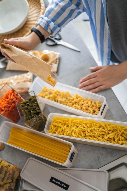 Top view female housewife placing sorting different kinds of vegan pasta into pp boxes