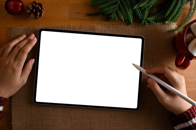 Top view A female using digital tablet at her desk with a Christmas decoration