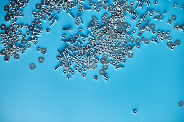 Top view, flat lay Metal screw, nuts and bolts on blue background, Working tools, Fixing elements