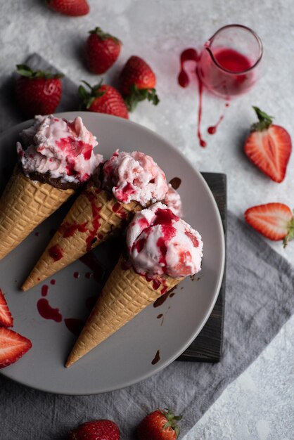 Top view flat lay pink ice cream in waffle cones on plate with fresh strawberries