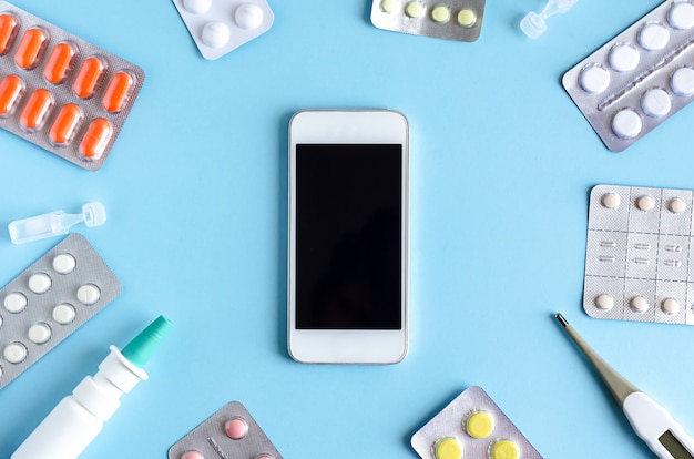 top view, flat lay of tablets, medicines, nasal spray, thermometer, antipyretic on blue