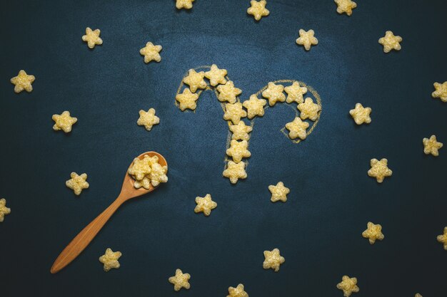 Photo top view flat lay taurus horoscope sign made from crispy corn stars on a black