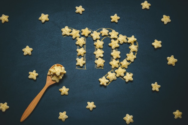 Top view flat lay virgo horoscope sign made from crispy corn stars on a black