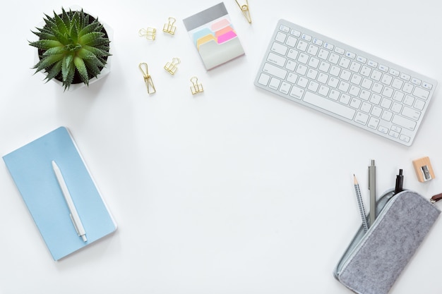 Top view and flat lay of workspace with notebook and keyboard mobile phone, green flower, pen box and pencil