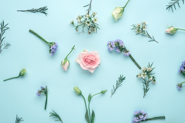 Top view flower composition, inflorescences rose, eustoma, limonium on blue background, flat lay