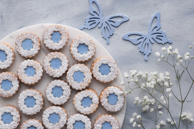 Top view of flower Linzer cookies with blue glazing  decorated with flowers and butterflies