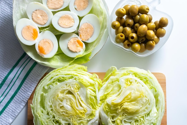 top view of food ingredients eggs green olives and lettuce for salad preparation