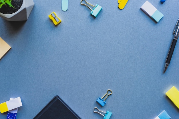 Top view of frame from stationery and plant on blue background