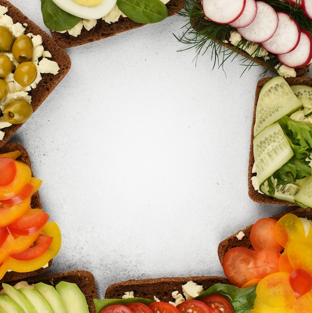 Top view frame of vegetables sandwiches. Open faced sandwiches in round on stone background with copy space.