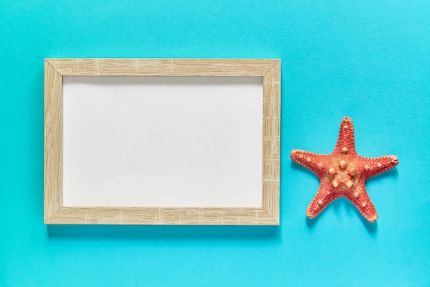 Top view of frame with seashells and starfish on blue. Summer vacation concept. Sea flat lay