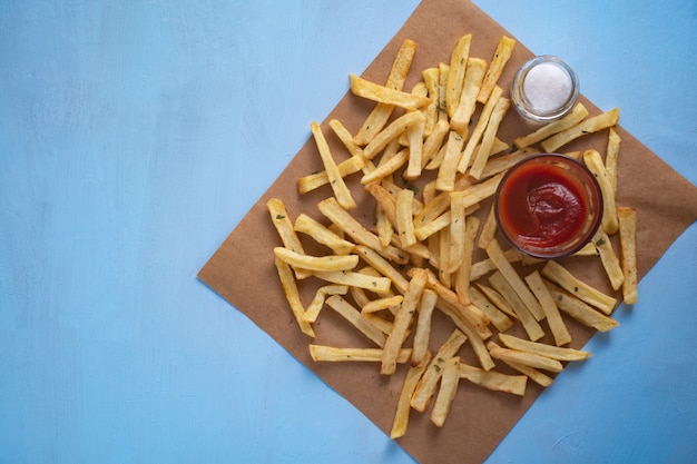 Top view of french fries with salt and ketchup