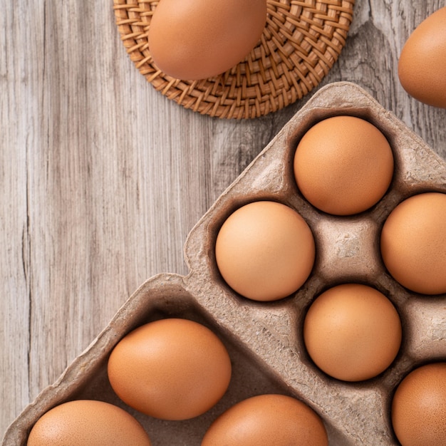 Top view of fresh brown chicken eggs in a kraft paper egg carton on wooden table background