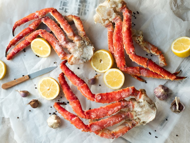 Top view of fresh crab phalanges with lemon and spices on rumpled paper.