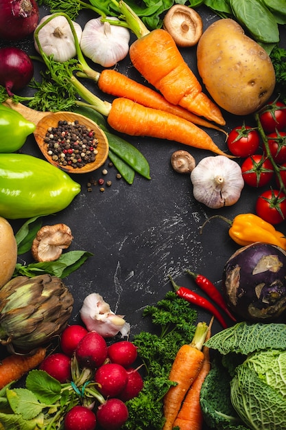 Top view of fresh farm organic vegetables, herbs and wooden spoon on rustic black concrete background. Autumn harvest, local market or clean healthy eating concept with space for text