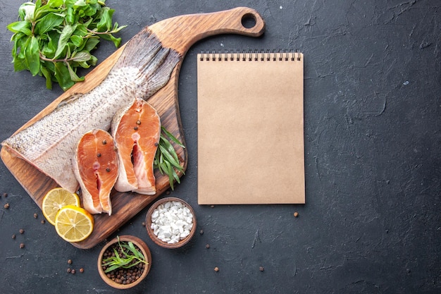 Top view fresh fish slices with lemon and greens on dark background meal seafood health meat dinner food ocean