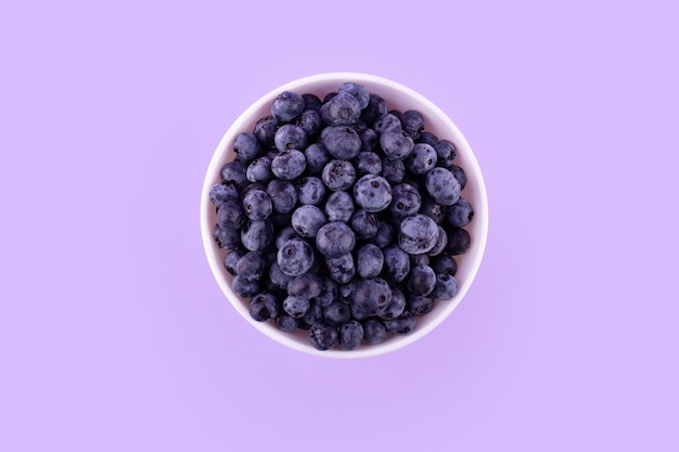 Top view of fresh juicy ripe blueberrie in bowl isolated on purple Flat lay copy space Healthy berry