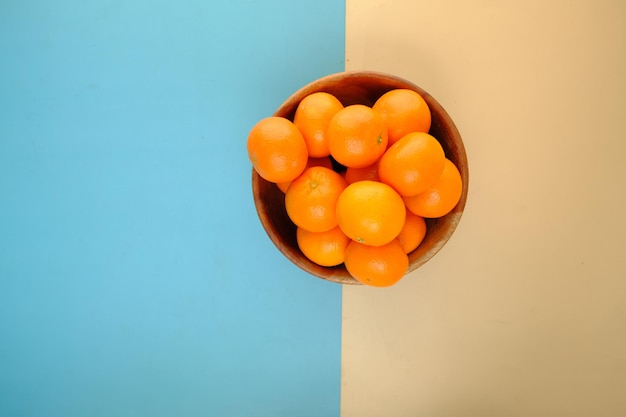 Top view of fresh orange fruit in a bowl on color background