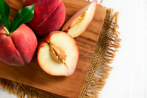 Top view of Fresh peaches on wood plate and white wood background