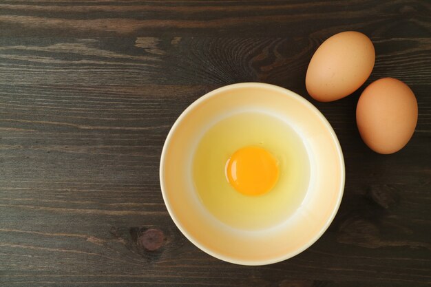 Top view of fresh raw egg in a bowl on wooden table