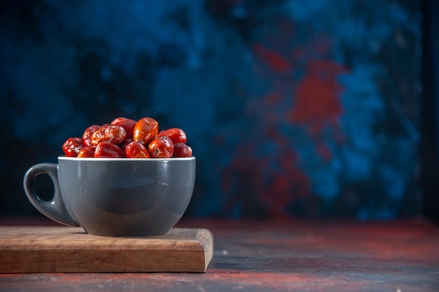 Top view of fresh raw silverberry fruits in a gray color cup on wooden board on the right side on mix colors background