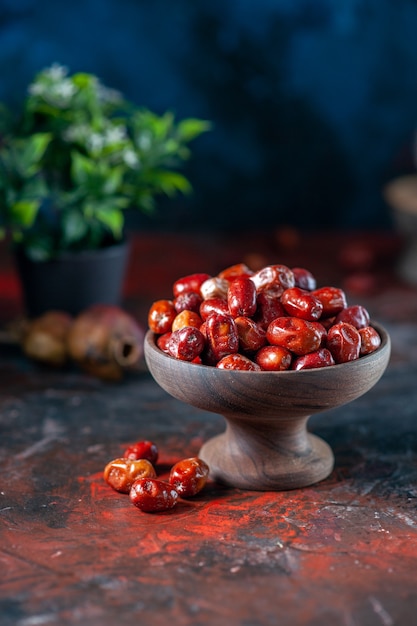 Top view of fresh raw silverberry fruits inside and outside of a wooden bowl and flower pot on mix colors background