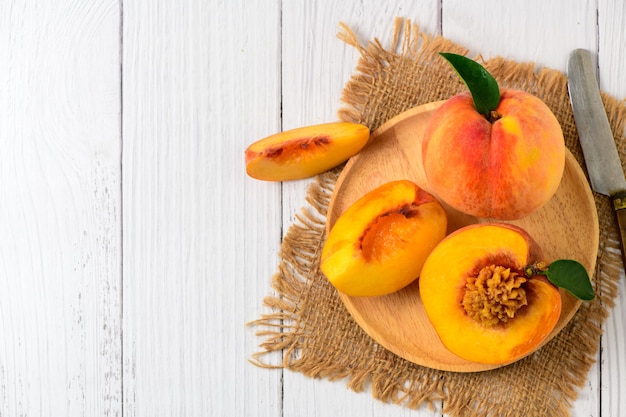 Top view of Fresh sweet sliced peach with green leaf on wood plate. Peach fruits