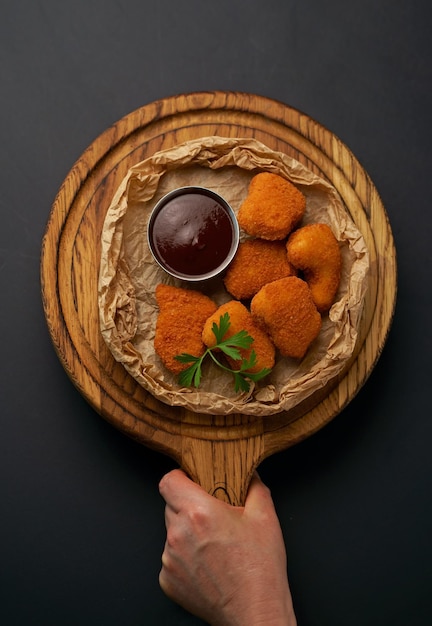 Top view of fried chicken fillet in breadcrumbs and sauce isolated on black background Grilled chicken on a board in the hands of a waiterWeb banner text design