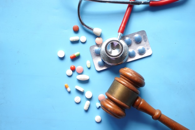 Top view of gavel stethoscope and pills on white background