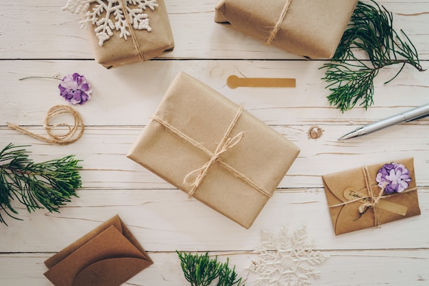 Top view of gift box and christmas card on wooden table with xmas decoration.