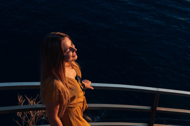 Top view of girl on stairs leaning against handrails against sea