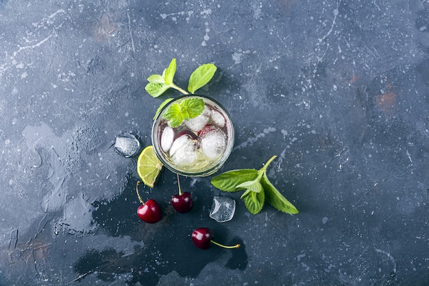 Top view of glass of summer lemonade or ice tea on grey textured background