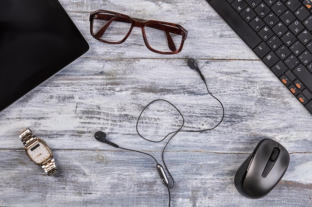 Top view glasses and earphones with mouse gray desk background