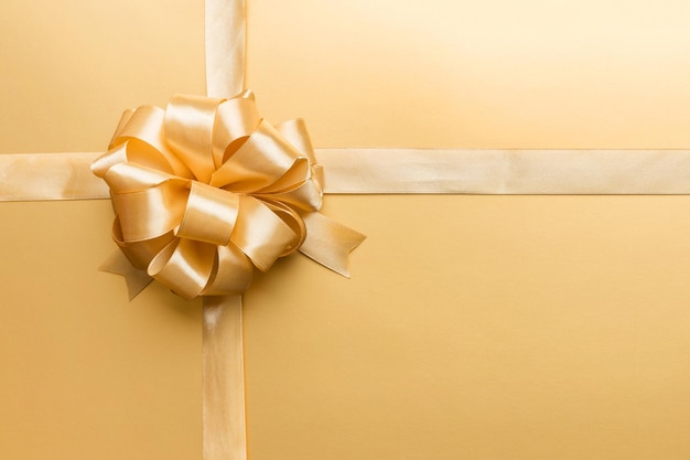 Top view of gold ribbon rolled and yellowbow isolated on colored background Flat lay with copy space