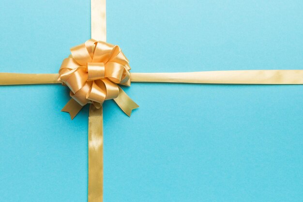 Top view of gold ribbon rolled and yellowbow isolated on colored background Flat lay with copy space