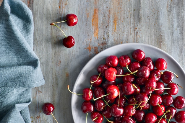 Top view on the gray plate of cherries on wood