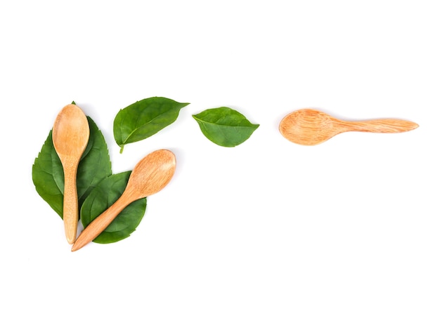 Top view of green leaves with wooden spoons isolated