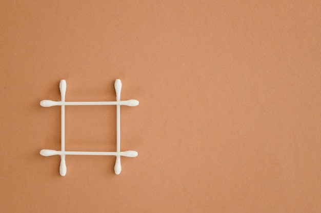 Top view of grid made of cotton swabs on beige background