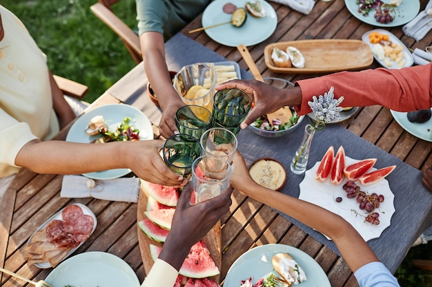 Top view at group of african american people clinking glasses over table with delicious food outdoor