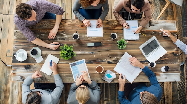 Top view of a group of business people sitting around a wooden table and having a meeting They are all wearing casual clothes and look relaxed